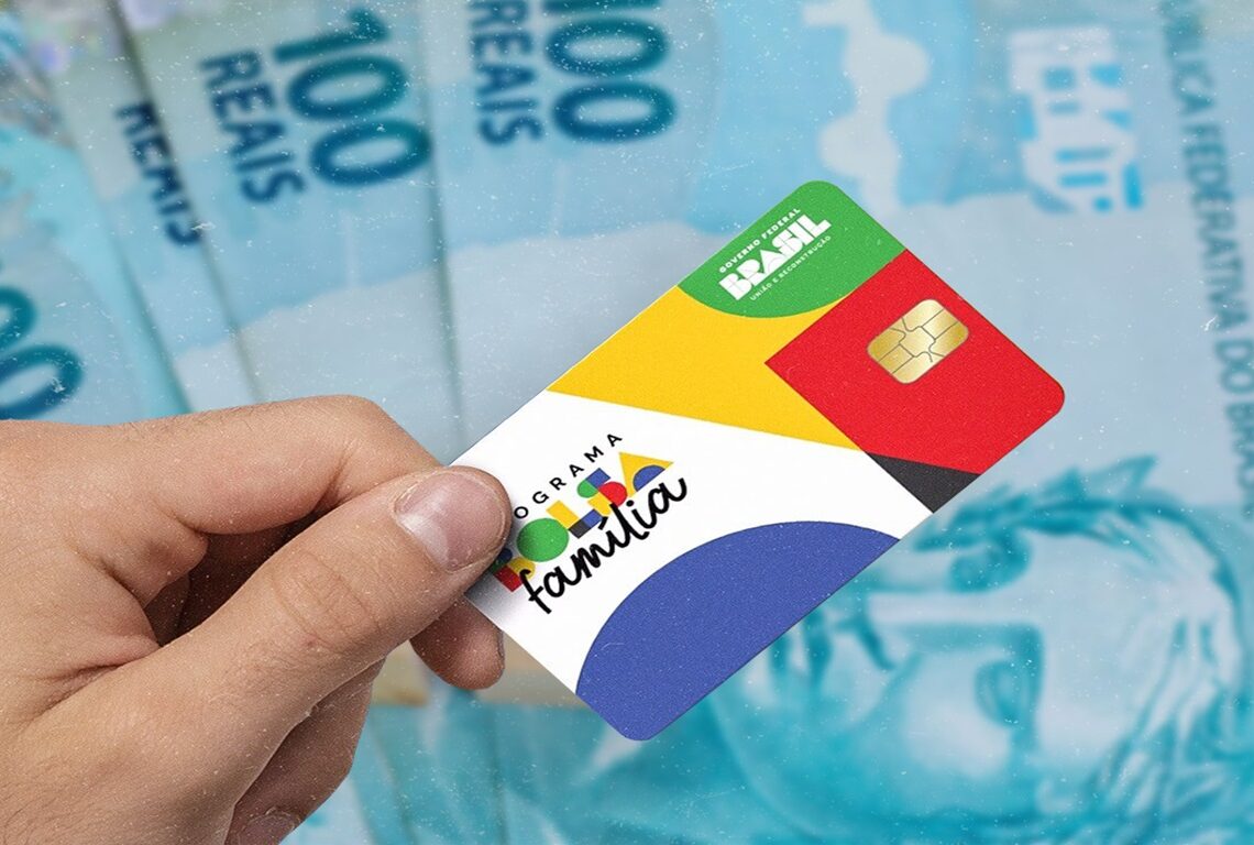 Cartão do Bolsa Família com cédulas de R$100 ao fundo